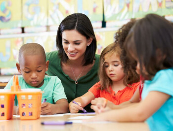 Photo of teacher working with small children in classroom