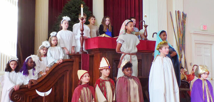 Children standing in and around the pulpit at First Unitarian Church, dressed in costume for the Christmas pageant