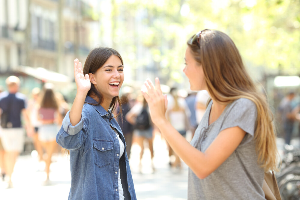 two-happy-young-women-greeting-each-other-on-the-street