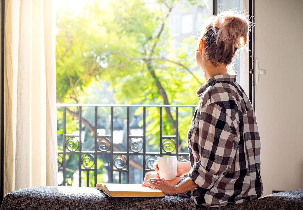 young-woman-drinking-coffee-looking-out-window-thinking