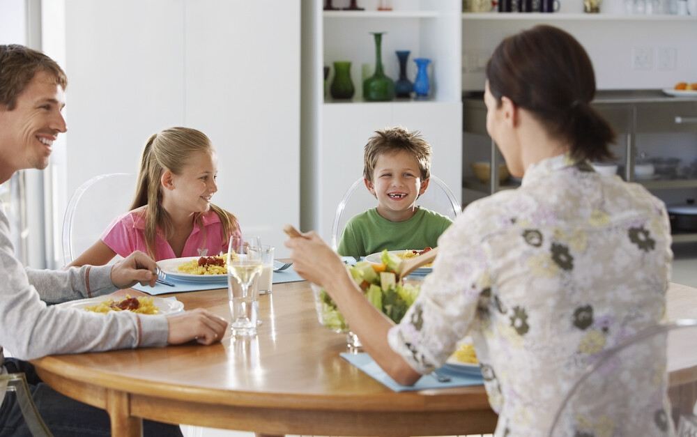 parents-and-two-young-kids-happily-eating-dinner-together