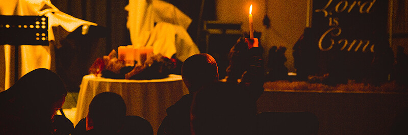 Boy holds up candle during Capital Community Church's candle light service in Beijing, China