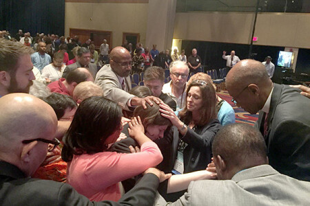 Clergy members surround T.C. Morrow in prayer following the vote not to commission her.