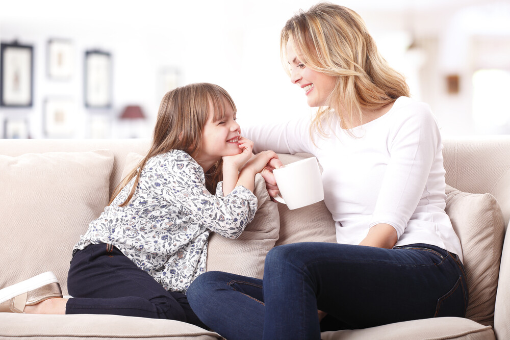 mom-and-young-daughter-happily-sitting-together-on-the-sofa