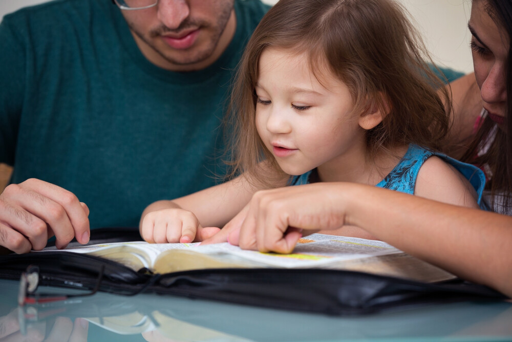 mother-and-father-showing-young-daughter-a-verse-in-the-Bible