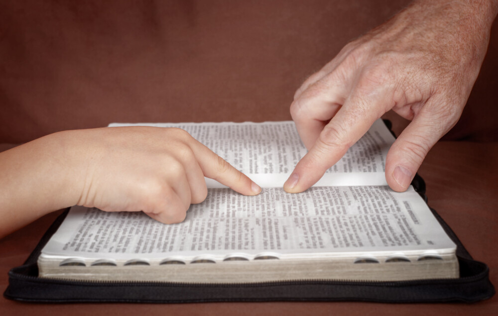close-up-of-father's-hand-showing-child-something-from-the-Bible