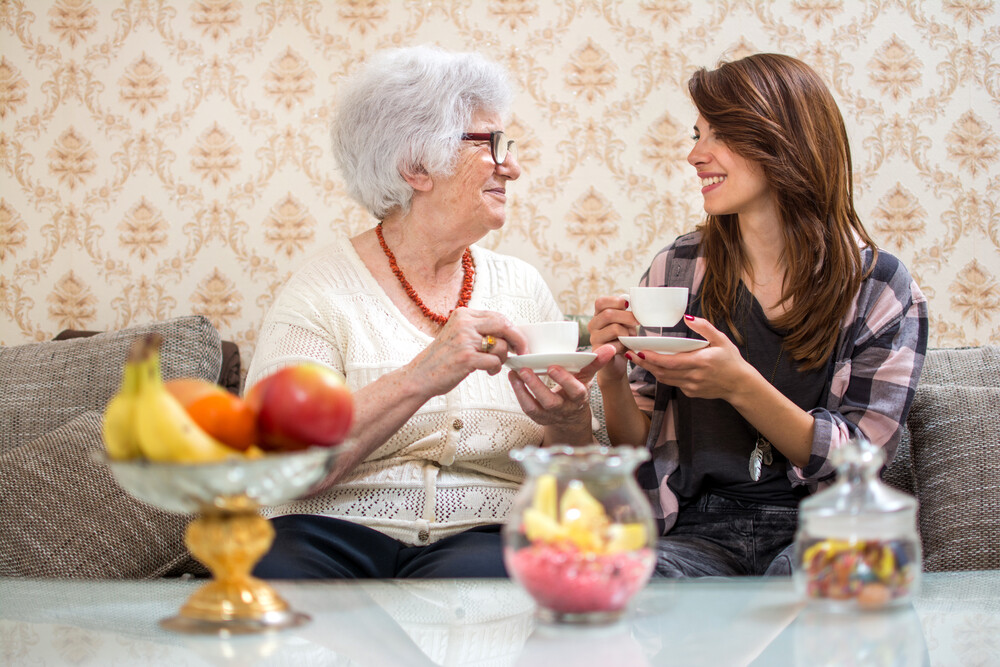young-woman-drinking-tea-with-an-elderly-woman-in-her-home
