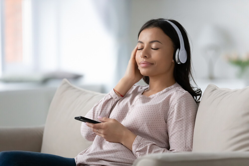 young-woman-sitting-on-the-sofa-relaxing-listening-to-headphones