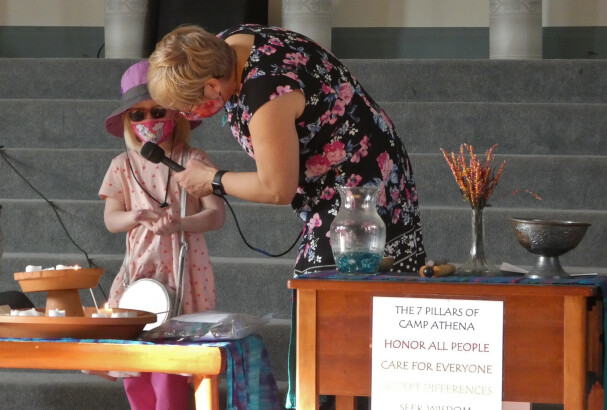 An adult holding a microphone for a child at children's chapel