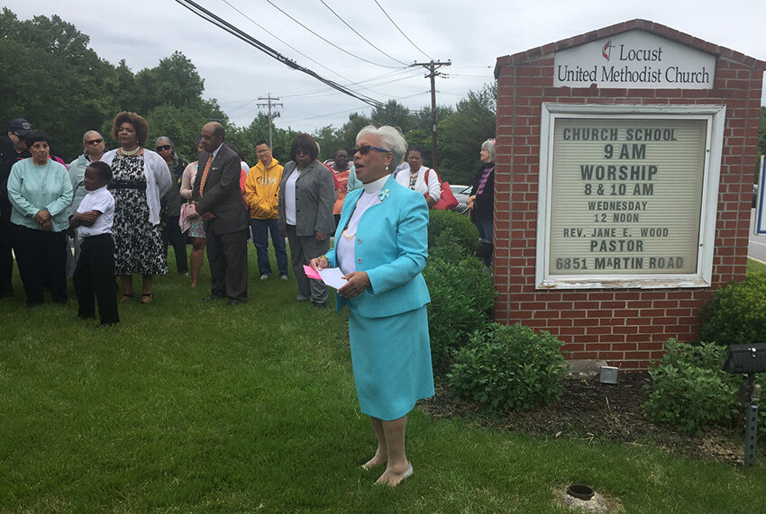 The Rev. Jane Wood leads a May 21 community prayer service in front of the church sign defaced by vandals.