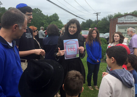 Rabbi Susan Grossman holds a photocopy of the defaced church sign at Locust UMC as children from her temple look on.  Grossman leads the Beth Shalom congregation in Columbia, within walking distance of Locust.
