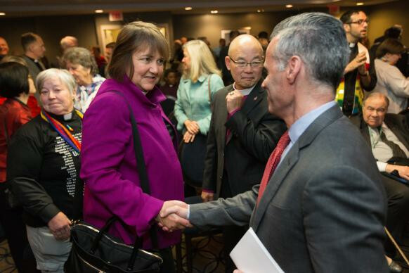 Bishop Karen Oliveto (left) and the Rev. Walter Fenton (right) shake hands during the April 25 oral hearing before the United Methodist Judicial Council meeting in Newark, N.J. Fenton is the analyst for Good News, which advocates that the church hold the line on homosexuality teachings. Photo by Mike DuBose, UMNS.