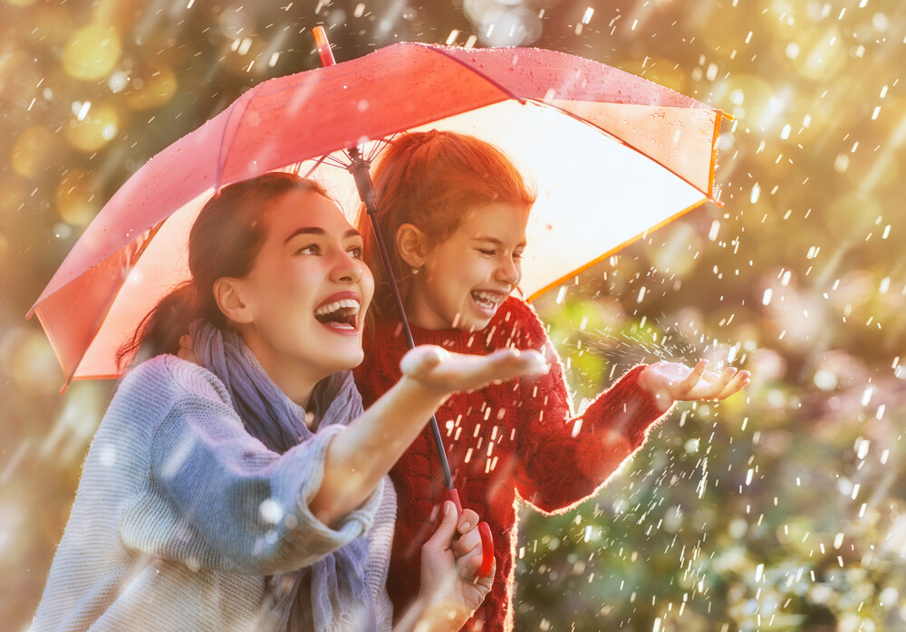 young-mom-and-her-daughter-with-umbrella-laughing-as-they-feel-the-rain