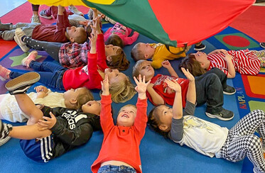 kids laying on ground under a suspended parachute