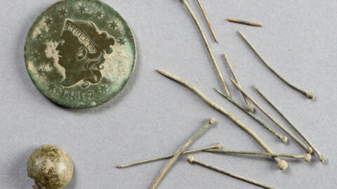 An old coin and a pile of pins