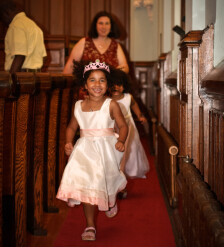 Two girls in baptismal dresses running down aisle and smiling