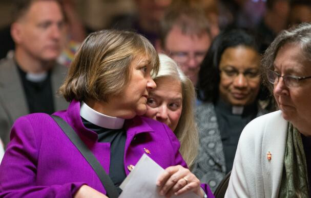 Bishop Karen Oliveto (left) leans over to speak with her wife, Robin Ridenour (behind Oliveto) prior to a meeting of the United Methodist Judicial Council in Newark, N.J. The denomination's top court ruled on April 28 that the consecration of a gay bishop violates church law. At right is Bishop Elaine Stanovsky. Photo by Mike DuBose, UMNS.
